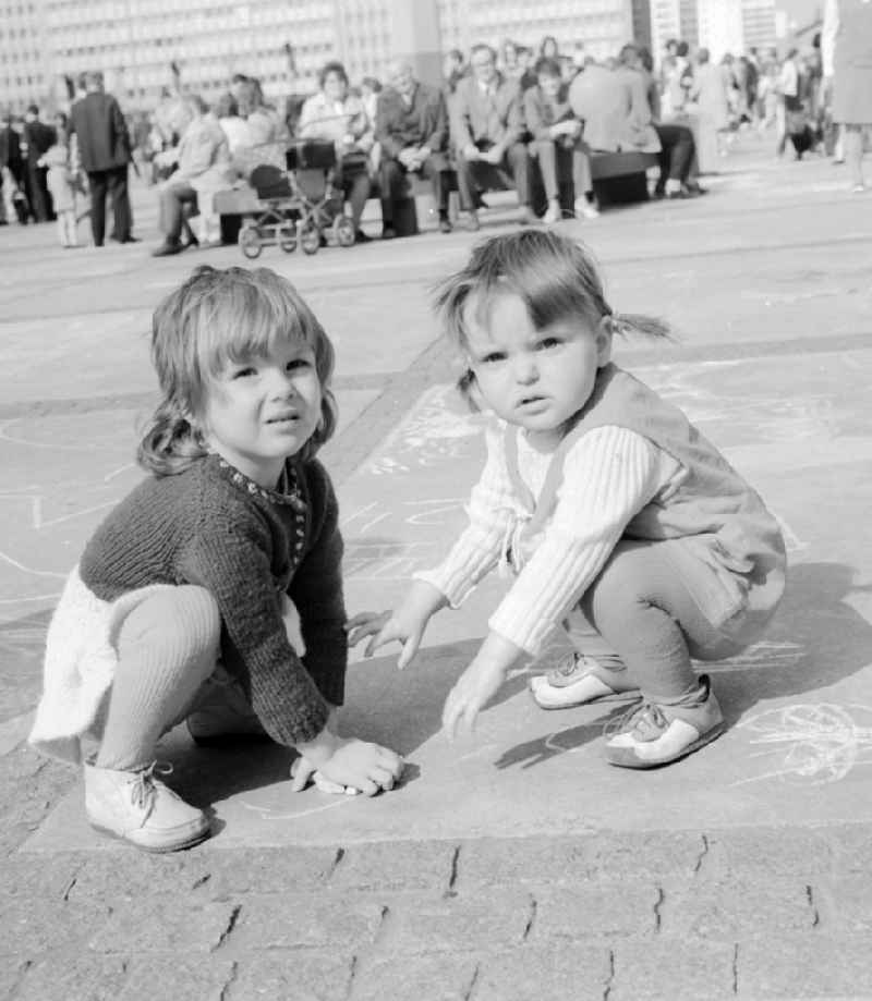 Small children draw with chalk on the Alexanderplatz in Berlin, the former capital of the GDR, German Democratic Republic
