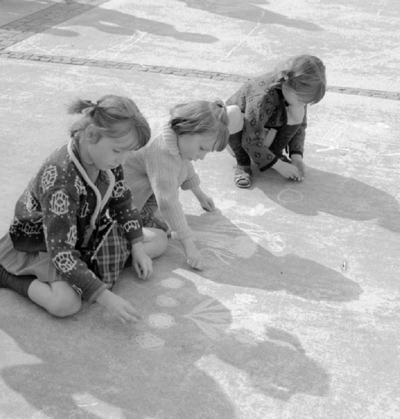 Small children draw with chalk on the Alexanderplatz in Berlin, the former capital of the GDR, German Democratic Republic