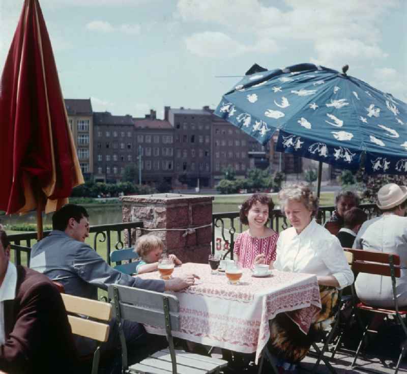 Young family by the open-air restaurant in the Ermelerhaus in Berlin, the former capital of the GDR, German democratic republic