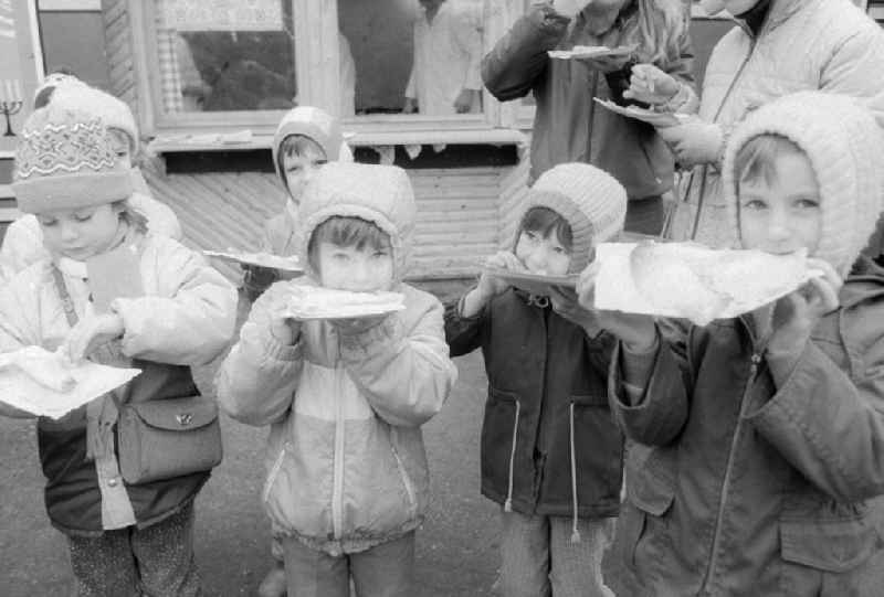 Children eat full pancakes on the Berlin Christmas fair in Berlin, the former capital of the GDR, German democratic republic. Today there stands at this point the shopping centre 'Alexa'