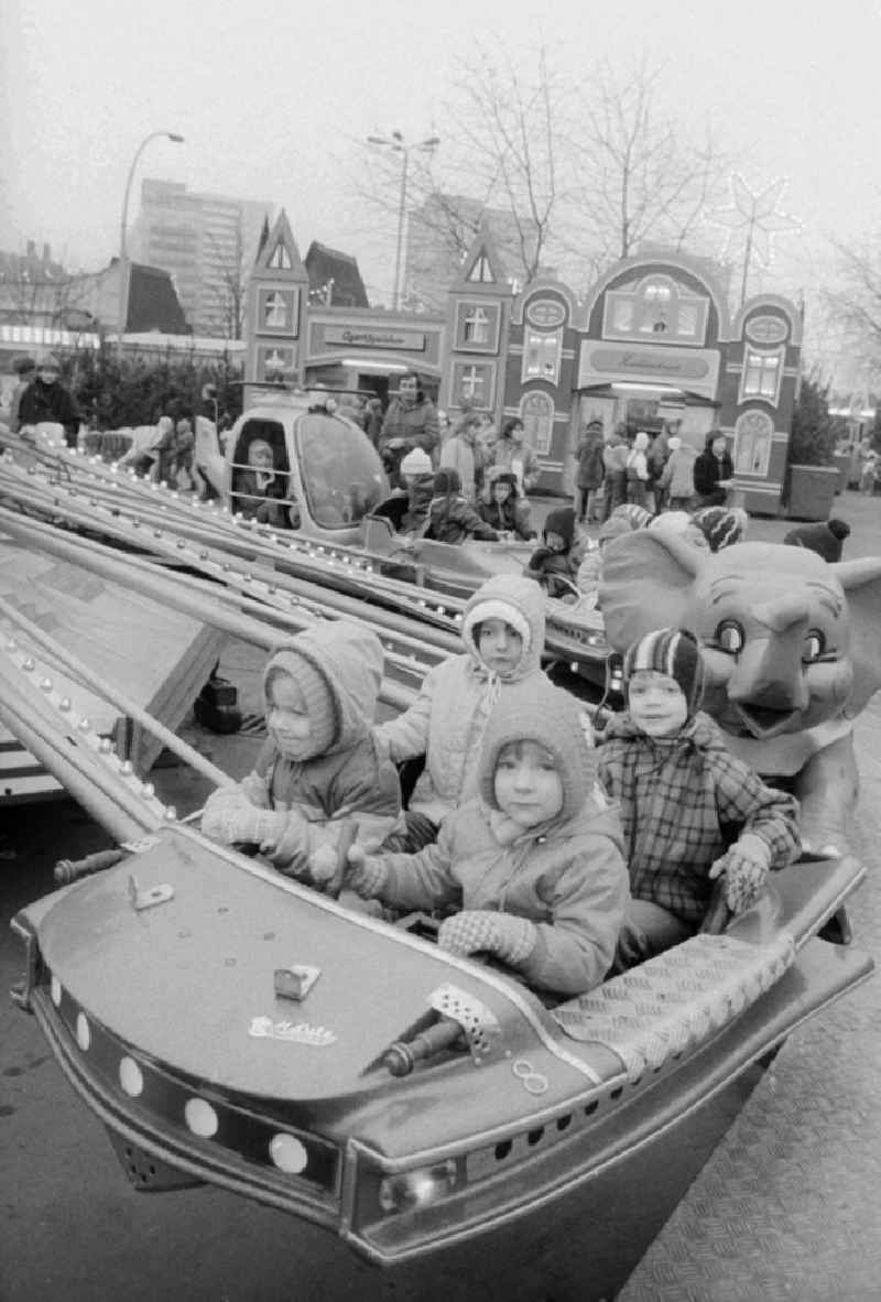 Children sit in a roundabout on the Berlin Christmas fair in Berlin, the former capital of the GDR, German democratic republic. Today there stands at this point the shopping centre 'Alexa'