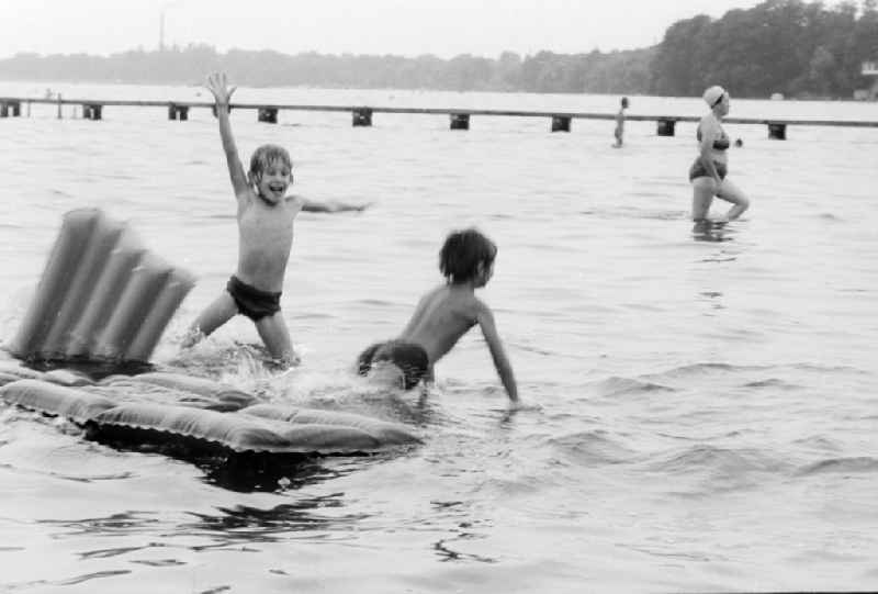 Children on an air bed on the Mueggelsee in the beach bath Mueggelsee in Berlin, the former capital of the GDR, German democratic republic