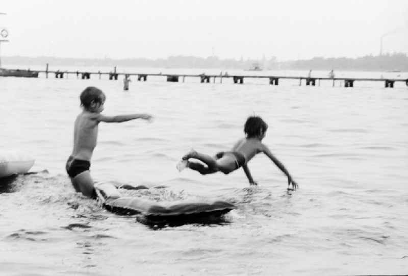 Children on an air bed on the Mueggelsee in the beach bath Mueggelsee in Berlin, the former capital of the GDR, German democratic republic