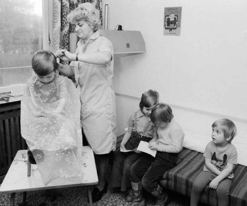 A hairdresser cuts to the children the hair in the nursery school in Berlin, the former capital of the GDR, German democratic republic
