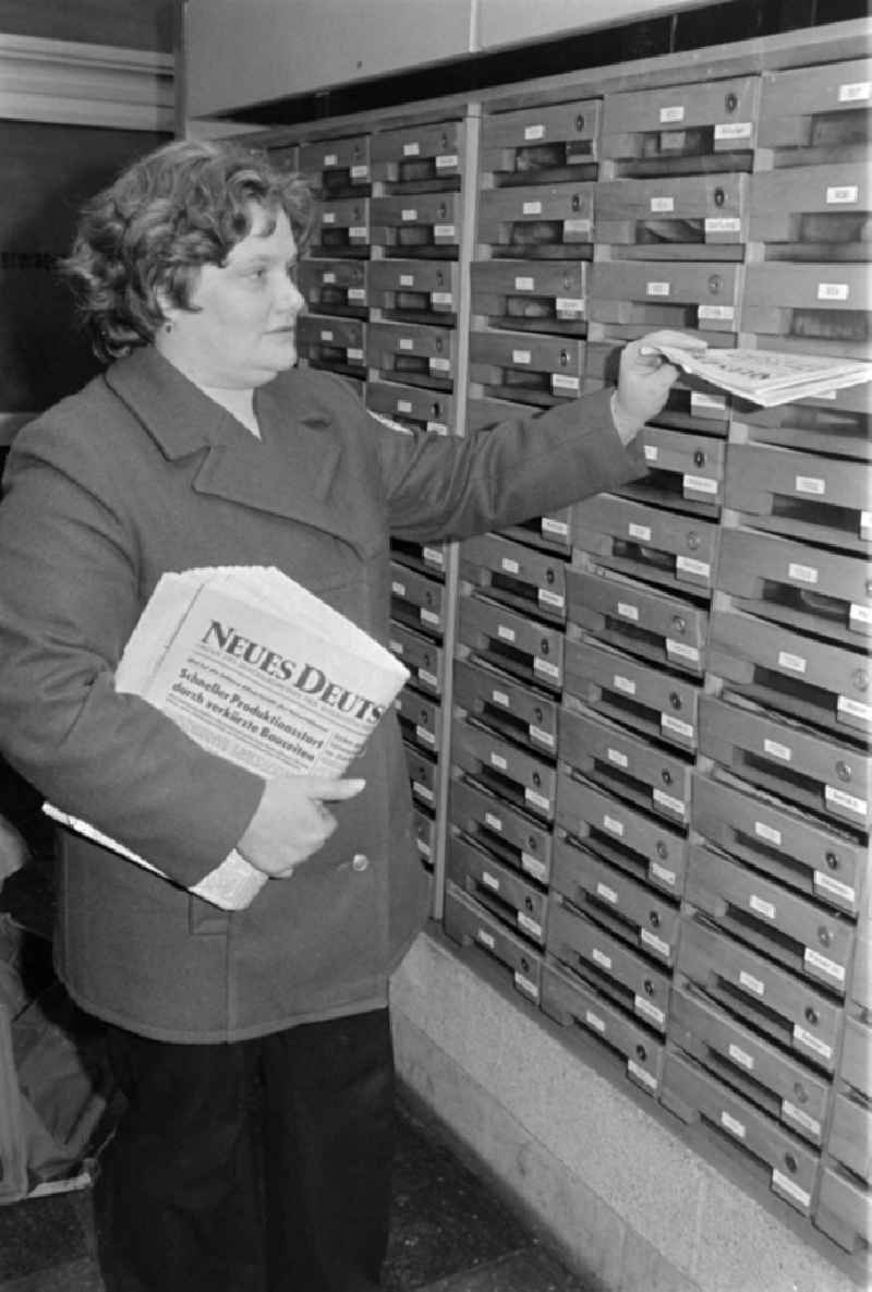 A postal woman puts the everyday newspaper 'Neues Deutschland' in mailbox of a block of flats in Berlin, the former capital of the GDR, German democratic republic