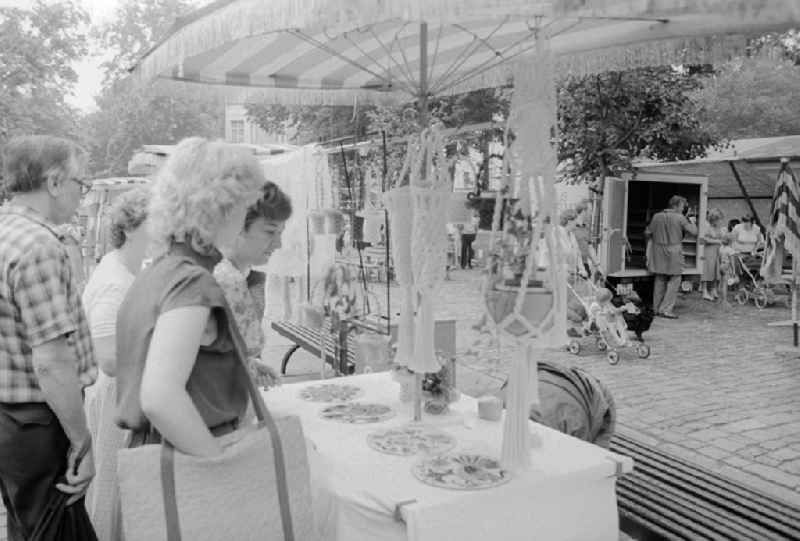 Customers in a sales state for macrame products at the weekly market on the place Askona in Berlin, the former capital of the GDR, German democratic republic