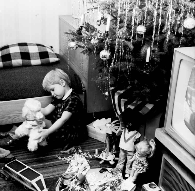 A small child plays with his Christmas presents under the Christmas tree in Berlin, the former capital of the GDR, German democratic republic