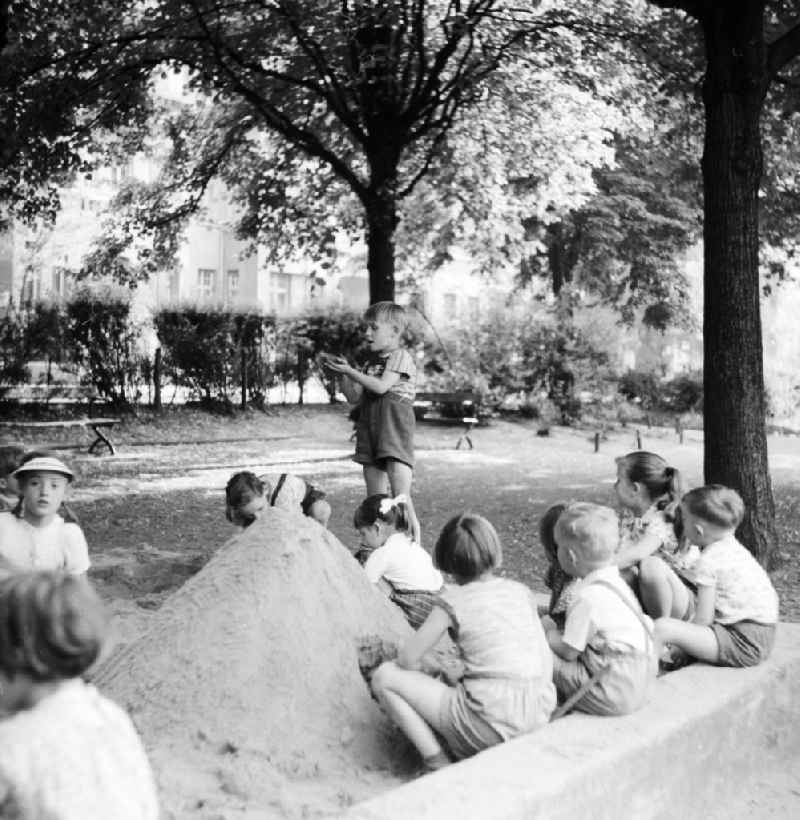 The playing children in the sandpit who build a sand castle, in Berlin, the former capital of the GDR, German democratic republic
