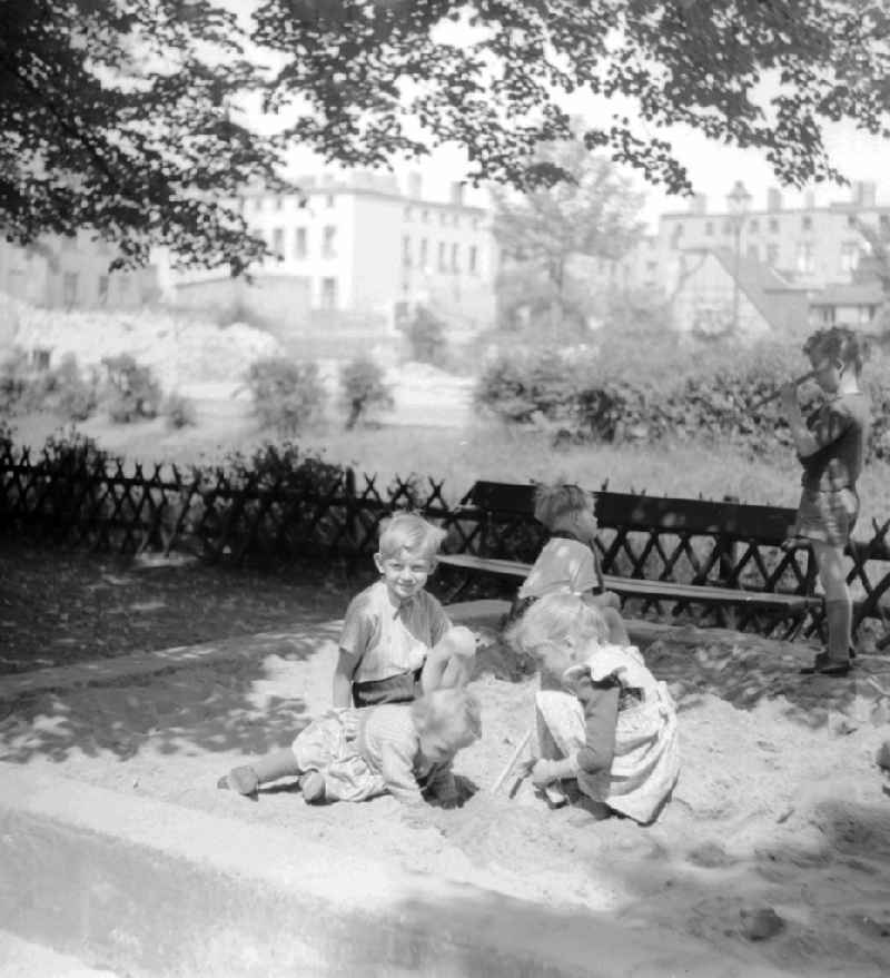 The playing children in the sandpit who build a sand castle, in Berlin, the former capital of the GDR, German democratic republic