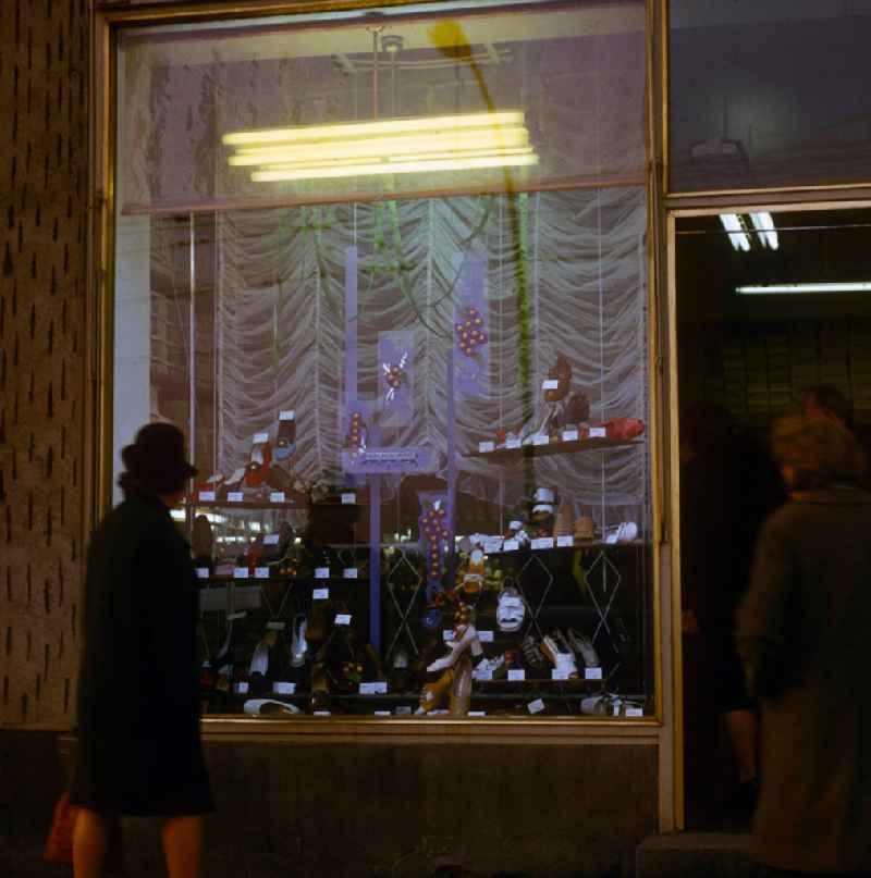 A woman looks to herself the new spring collection in the shop-window of a shoe store in in Berlin, the former capital of the GDR, German democratic republic