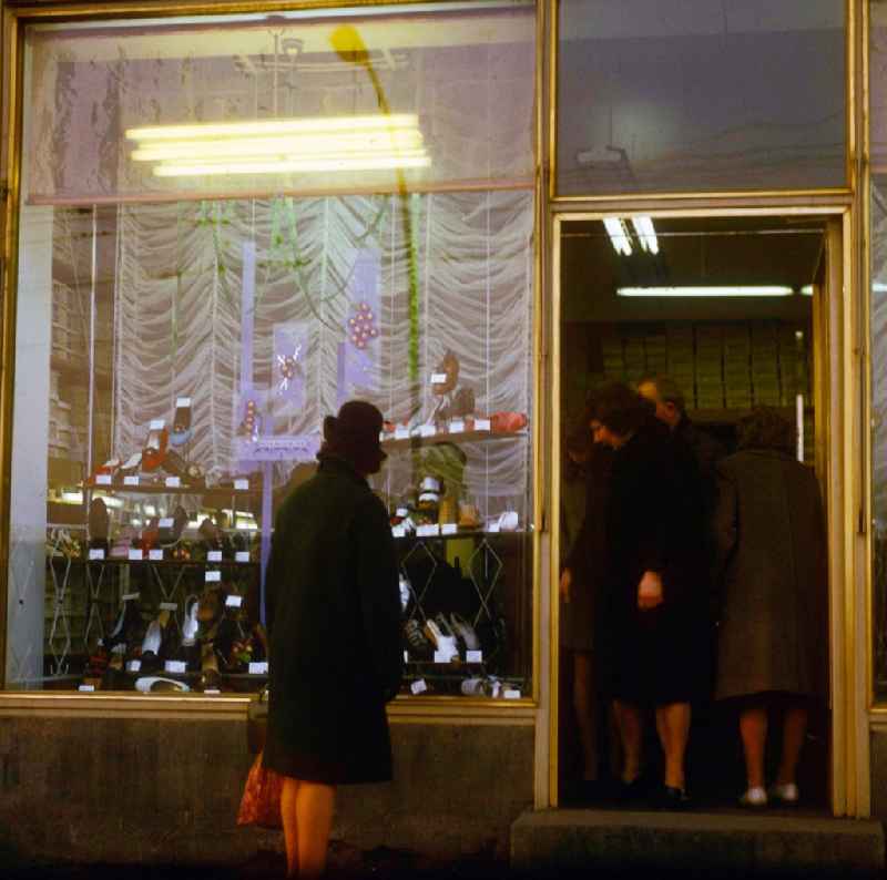 A woman looks to herself the new spring collection in the shop-window of a shoe store in in Berlin, the former capital of the GDR, German democratic republic