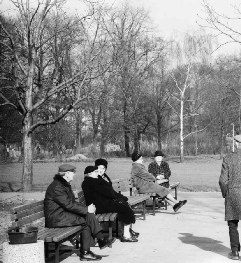 Pensioners sit on park-benches in the national park Friedrich's grove and enjoy the first sunrays in the spring in Berlin, the former capital of the GDR, German democratic republic