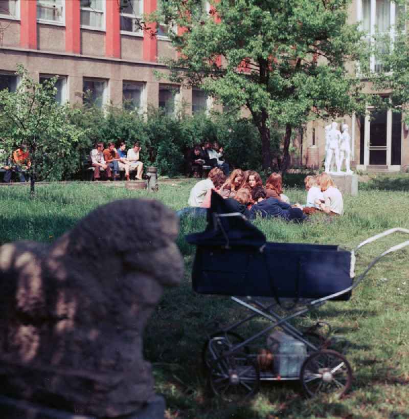 Students of the art college of Berlin white lake lie in the inner courtyard on the meadow and enjoy the sun in Berlin, the former capital of the GDR, German democratic republic