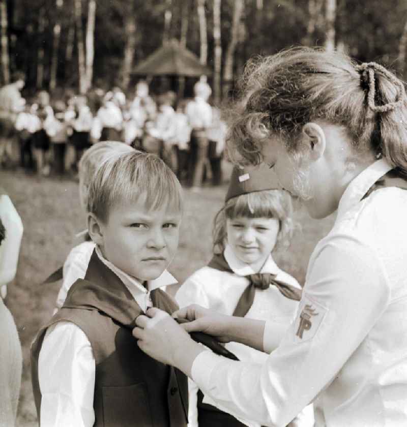 A young's pioneer of the 1st class receives solemnly his blue neckerchief from Thaelmann pioneer hands in Berlin, the former capital of the GDR, German democratic republic
