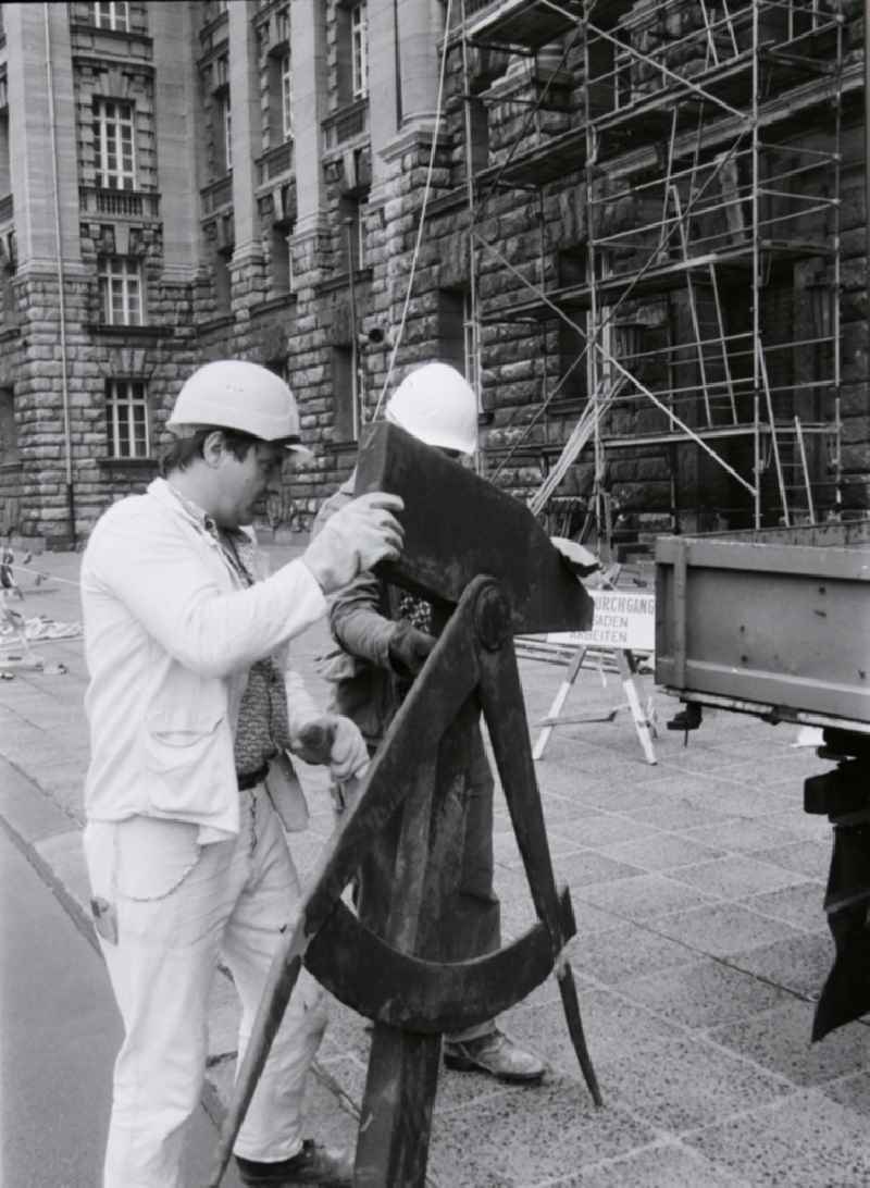 Workers remove the worker symbol at the Berliner Stadthaus of the former capital of the GDR, German Democratic Republic
