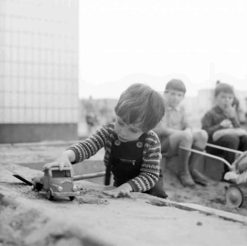 A small boy plays in the sandpit by a toys car in Berlin, the former capital of the GDR, German democratic republic