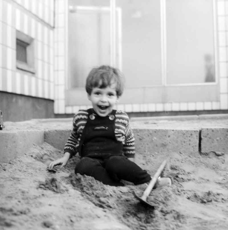 A small boy in a Kordlatzose plays in the sandpit in Berlin, the former capital of the GDR, German democratic republic
