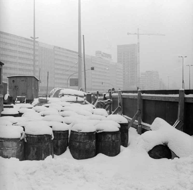 Snow-covered barrels on a construction site in Berlin, the former capital of the GDR, German Democratic Republic