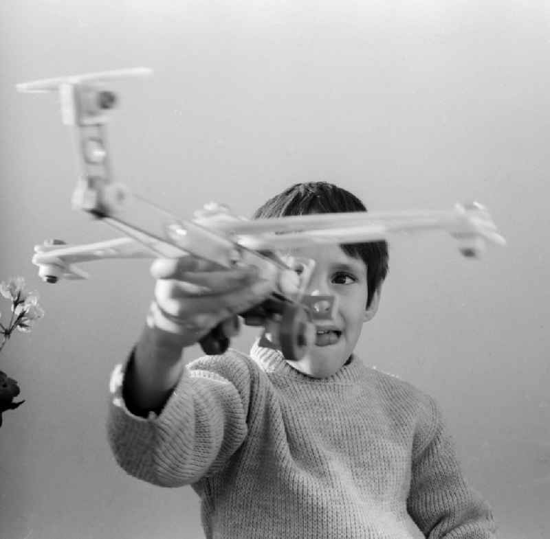A boy plays with an airplane made of plastic parts in Berlin, the former capital of the GDR, German Democratic Republic