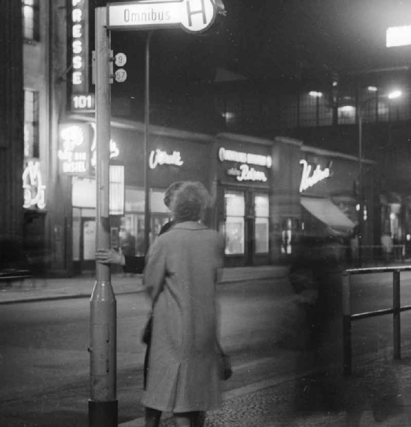 A woman waits in the evening at a bus stop for a bus at Friedrichstrasse in Berlin, the former capital of the GDR, German Democratic Republic