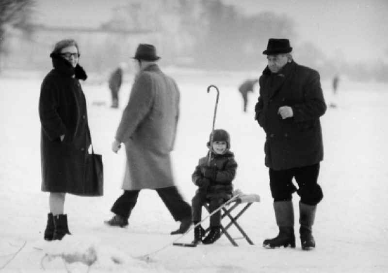 Grandparents with their grandson ice-fishing on a lake in Berlin, the former capital of the GDR, German Democratic Republic