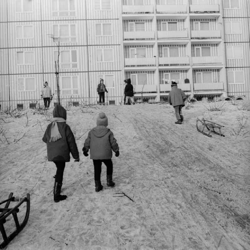 Children with sledges on a toboggan hill in a residential area in Berlin, the former capital of the GDR, German Democratic Republic