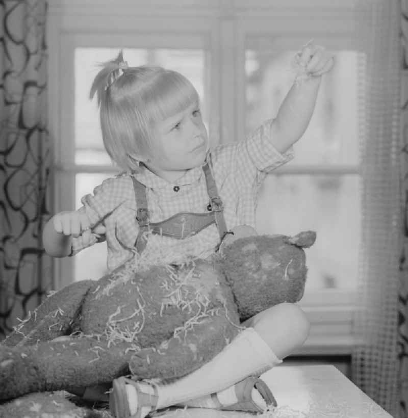 A child cuts up a teddy bear in Berlin, the former capital of the GDR, German Democratic Republic