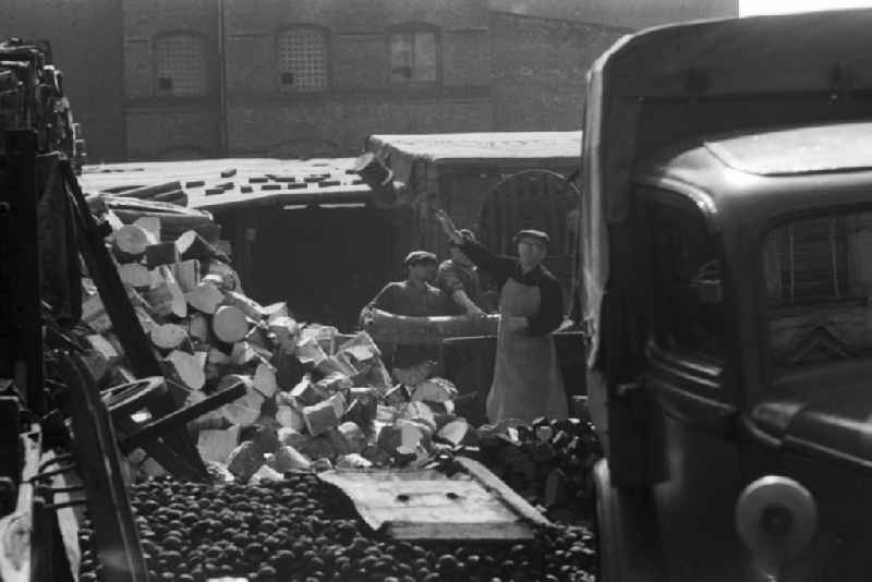 Employees of a fuel and coal trading company loading firewood, briquettes and so-called egg coal in Berlin, the former capital of the GDR, German Democratic Republic