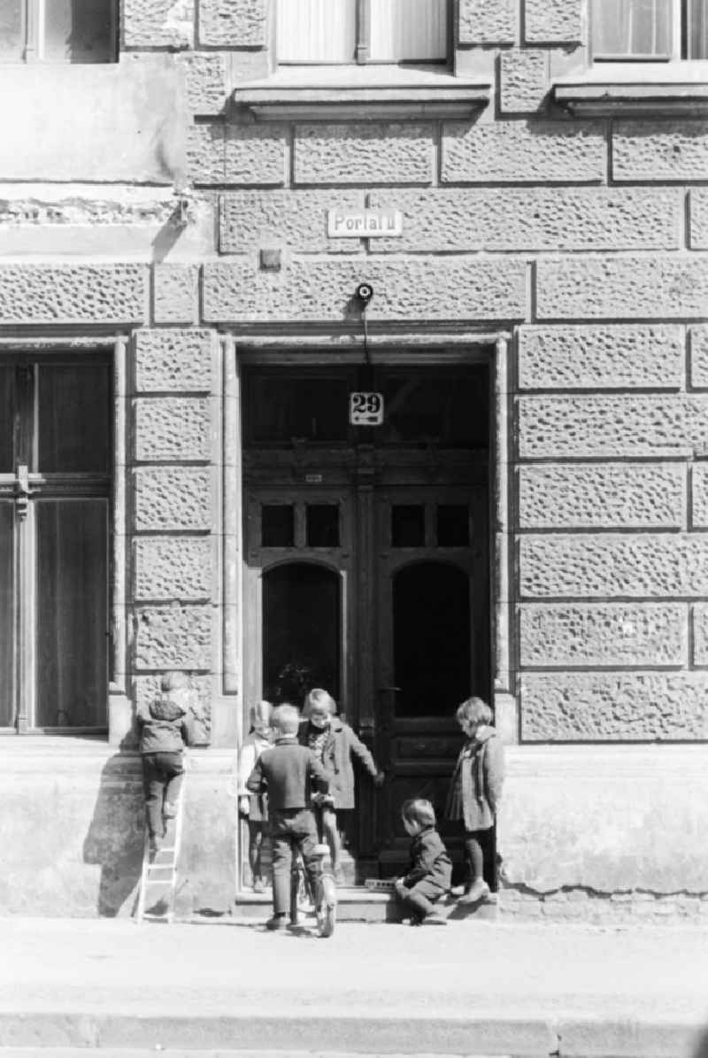 Children are playing in front of the entrance of an old building in Berlin, the former capital of the GDR, German Democratic Republic