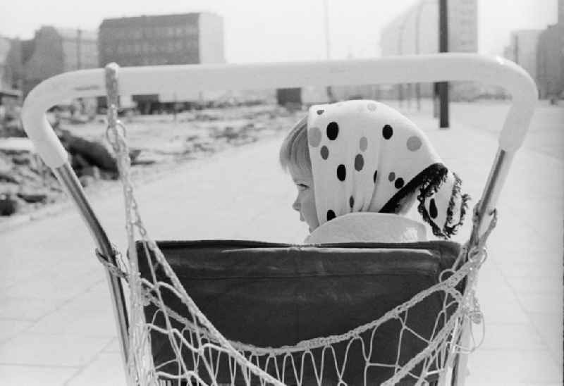 A little girl with a headscarf sits in a pram in Berlin, the former capital of the GDR, German Democratic Republic