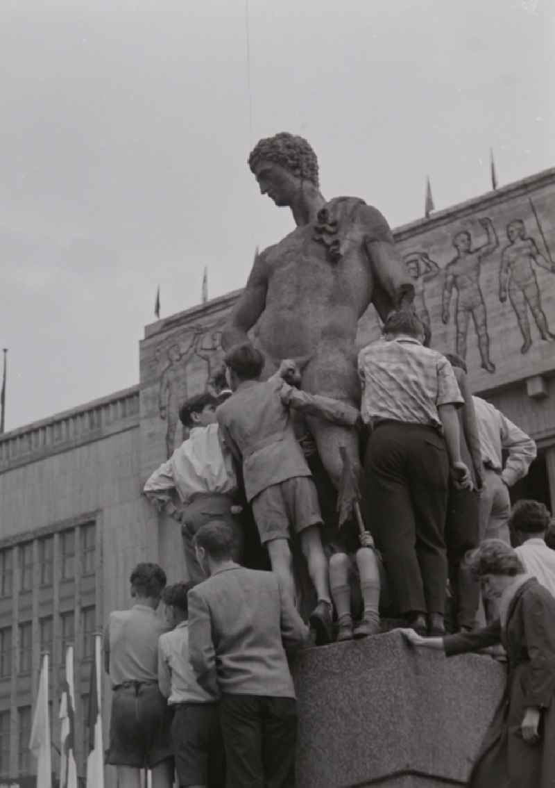 Fun and games for children and teenagers in front of a stone sculpture in front of the Deutsche Sporthalle on Stalinallee - today's Karl-Marx-Allee in the district Friedrichshain in Berlin, the former capital of the GDR, German Democratic Republic