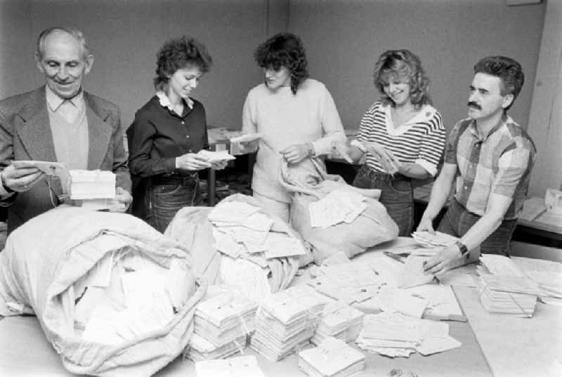 ND employees evaluating the mail for the restaurant competition of the newspaper Neues Deutschland in the Friedrichshain district of Berlin, the former capital of the GDR, German Democratic Republic. Several mailbags with cards lie on the table