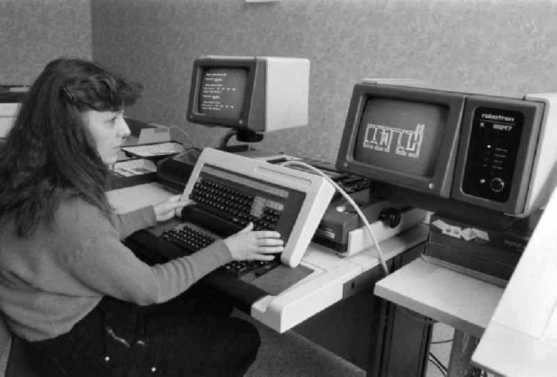 Female employee in project planning at the VEB ( Volkseigener Betrieb ) Baukombinat Koepenick in the district of Treptow-Koepenick in Berlin, the former capital of the GDR, German Democratic Republic. Woman sitting in front of a Robotron computer