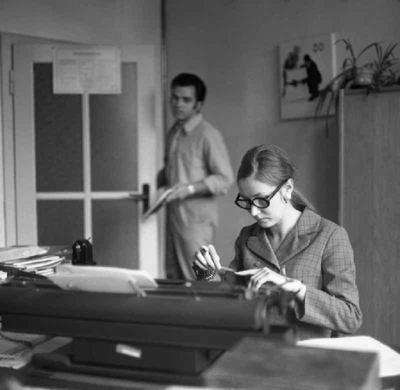 A secretary is observed by a colleague while filing her fingernails in the office. Everyday office life in Berlin, the former capital of the GDR, German Democratic Republic
