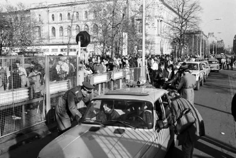 Lively crowd at the passport control point. Officers of the passport control unit of the Ministry for State Security in border troops uniforms check people and vehicles at the Invalidenstrasse border crossing point one day after the opening of the border and the fall of the Wall in Berlin, the former capital of the GDR, German Democratic Republic