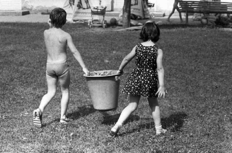 Boy and girl together carry a bucket in kindergarten in Berlin Eastberlin on the territory of the former GDR, German Democratic Republic