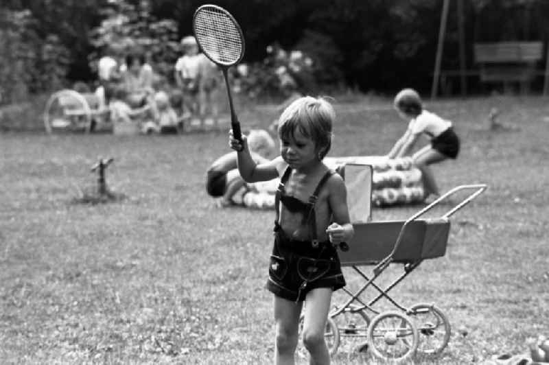 Boy in leather pants plays badminton in kindergarten in Berlin Eastberlin on the territory of the former GDR, German Democratic Republic
