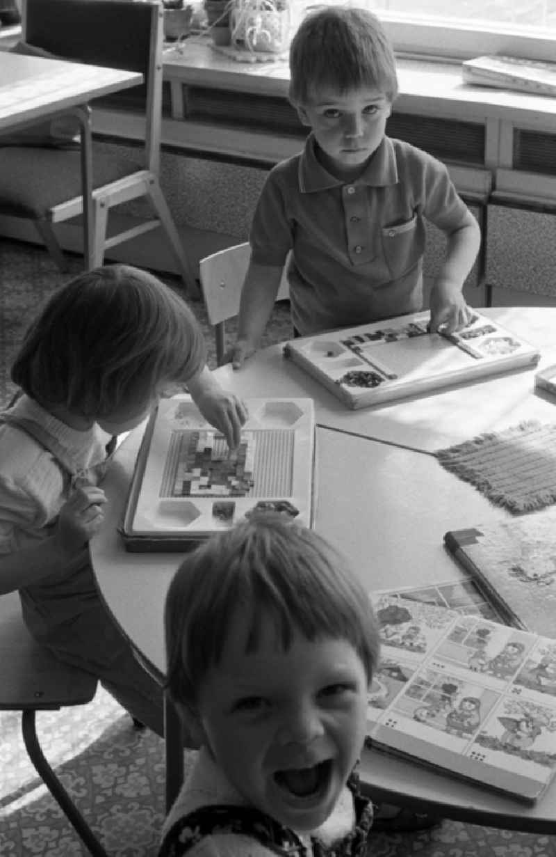 Children play at the table with a ' Gloria Mosaic ' peg game in Berlin Eastberlin on the territory of the former GDR, German Democratic Republic