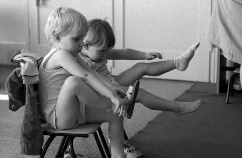 Preparing for a nap in the kindergarten in Berlin Eastberlin on the territory of the former GDR, German Democratic Republic. Toddlers take off their clothes together