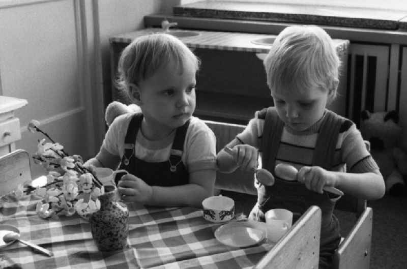Toddlers sit at a table in kindergarten for a meal in Berlin Eastberlin on the territory of the former GDR, German Democratic Republic
