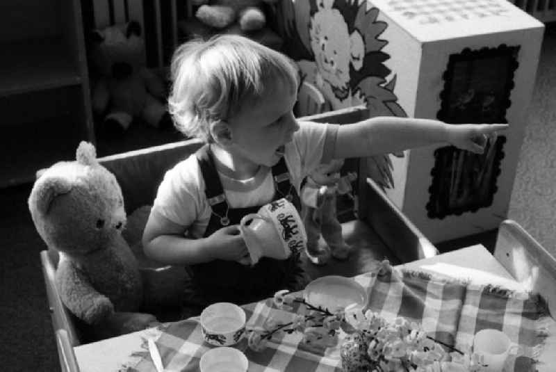 Toddler sit at a table in kindergarten for a meal in Berlin Eastberlin on the territory of the former GDR, German Democratic Republic
