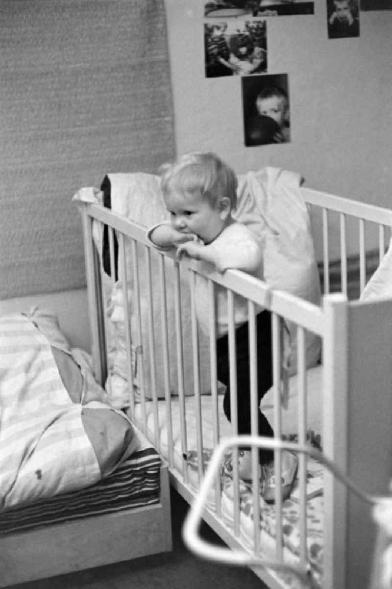 A toddler stands in his bed in Berlin Eastberlin on the territory of the former GDR, German Democratic Republic