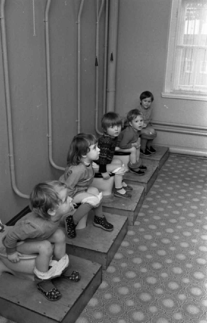 Small children crouching next to each other in the toilet in a kindergarten in Berlin East Berlin on the territory of the former GDR, German Democratic Republic