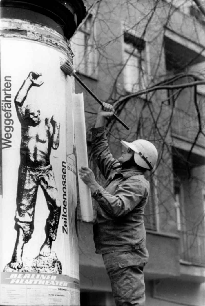 Advertising for beim Bekleben mit einem Kunstausstellungsplakat on an advertising pillar on a sidewalk in the district Mitte in Berlin Eastberlin on the territory of the former GDR, German Democratic Republic