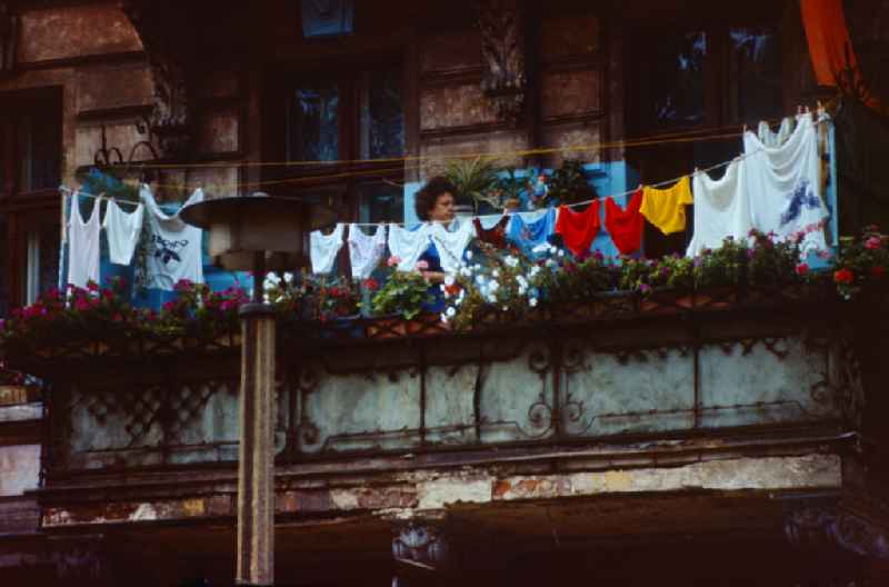 Woman hangs up her freshly washed laundry on the balcony in Berlin on the territory of the former GDR, German Democratic Republic