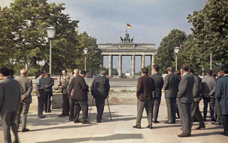 Tourists and visitors in front of the blocking strip at the Brandenburg Gate with the Quadriga at Pariser Platz in Berlin, the former capital of the GDR, German Democratic Republic
