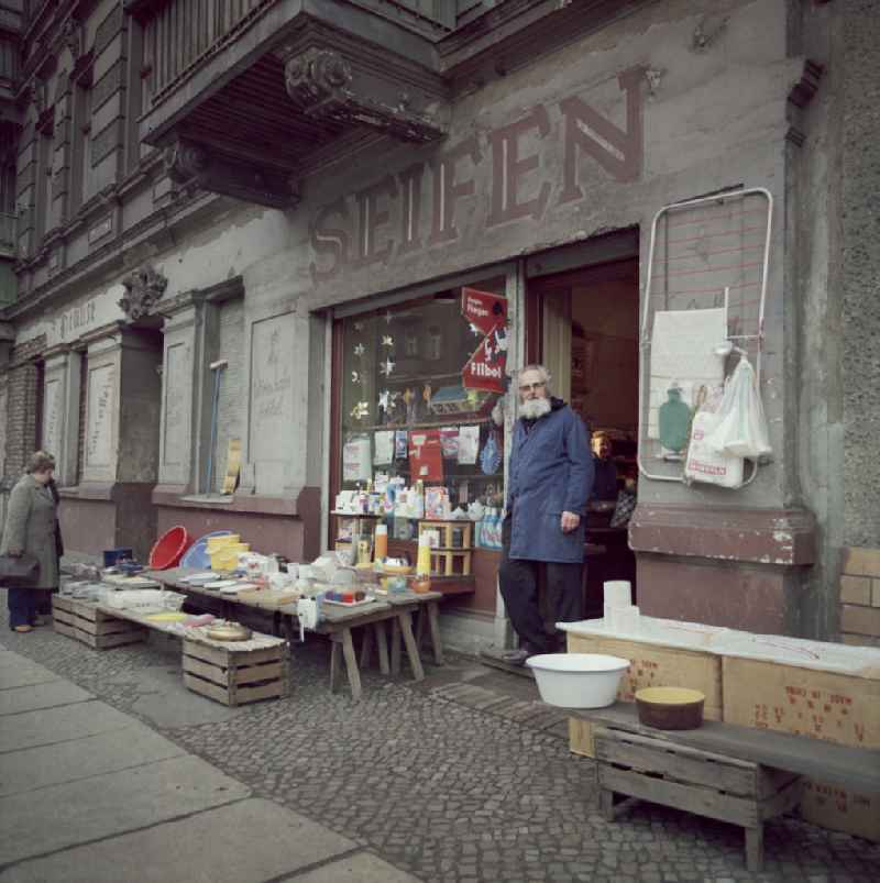 Gray-bearded dealer and owner of a soap shop - drugstore on Marienburger Strasse in front of his shop door in the Boetzowviertel district in Berlin East Berlin on the territory of the former GDR, German Democratic Republic