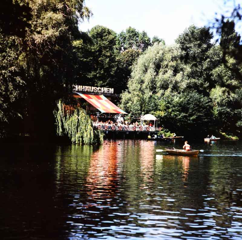 Visitors at the Café Milchhaeuschen and rowing boats on the lake in Berlin Weissensee, Eastberlin on the territory of the former GDR, German Democratic Republic