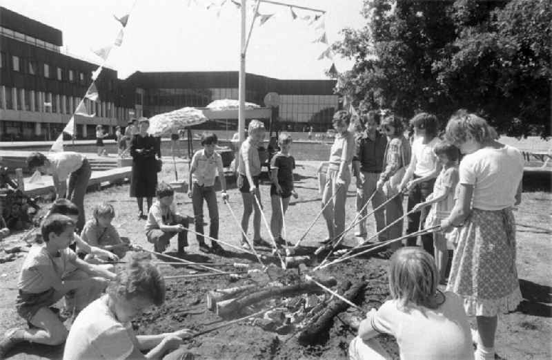 Children baking bread on an open fire on Children's Day on the grounds of the Pioneer Palace (today: Leisure and Recreation Centre FEZ ) in Berlin Koepenick in the territory of the former GDR, German Democratic Republic