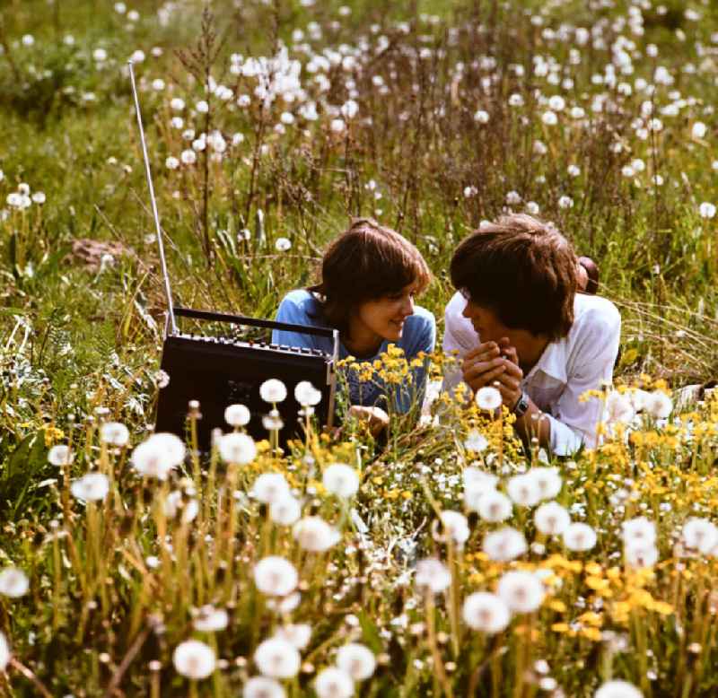 Young couple in front of a tape recorder on a meadow in Eastberlin on the territory of the former GDR, German Democratic Republic